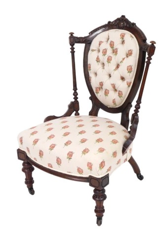 A Victorian walnut nursing chair, with a carved crest rail, rose decorated overstuffed button back and seat, raised on turned legs, brass capped on castors, 60 cm wide.