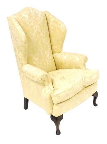 A George III mahogany wing back armchair, upholstered in patterned gold damask, raised on cabriole legs, 84cm wide.