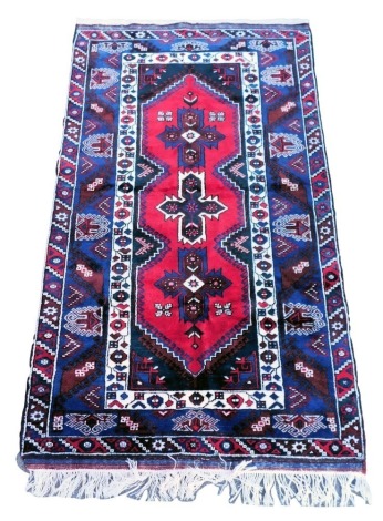 A Turkish Sultankoy red ground rug, the central field decorated with three floral, cross motifs, within repeating floral and foliate borders, 130cm x 210cm.