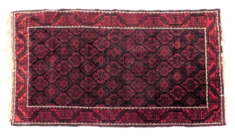 A Caucasian blue and red ground rug, with a central field of repeating medallions, within repeating geometric borders, 215cm x 117cm.