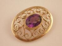 An amethyst 9ct gold scroll work brooch