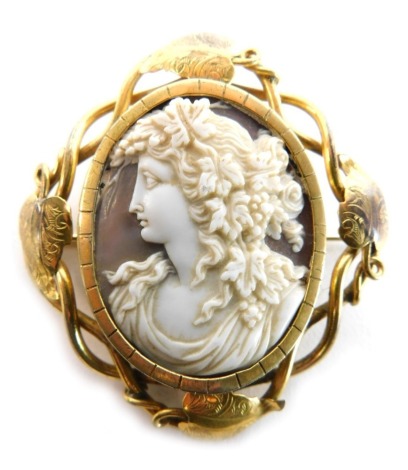 A 19thC carved oval cameo brooch, with classical female bust, profusely carved with fruiting vine ornamentation, within a pinchbeck open scroll mount with leaves, 5.5cm x 5cm.