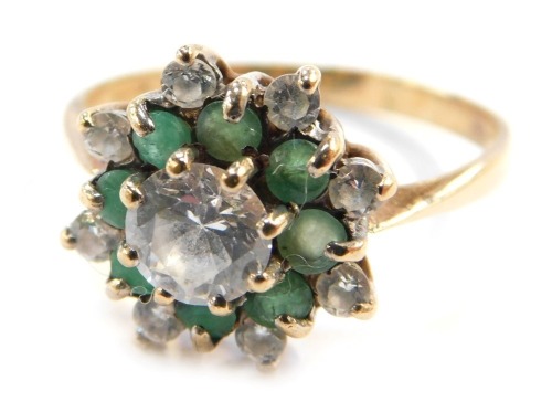 A gold flower head dress ring, set with emerald and CZ stones, formed as layers, hallmarks rubbed, size T, 3.3g all in.
