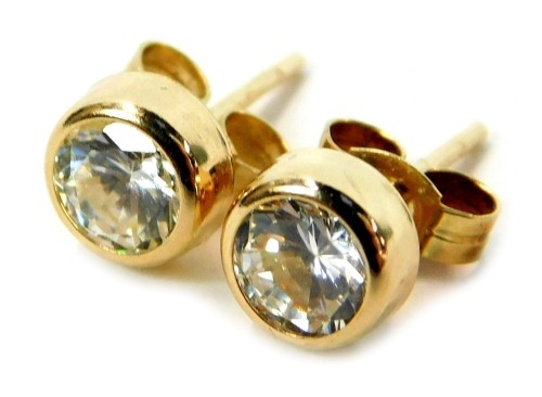 A pair of stud earrings, each with imitation diamond, in a rub over setting on single pin back with butterfly backs, yellow metal, marked 375, 0.8g all in, boxed.