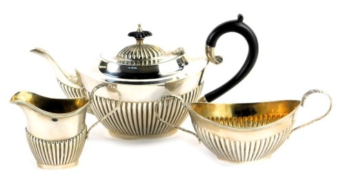 An Elizabeth II silver three piece tea service, comprising teapot, two handled sugar bowl and milk jug, each with part fluted decoration, WI Broadway & Co, Birmingham 1986, 24.31oz all in, the teapot 14.5cm high.