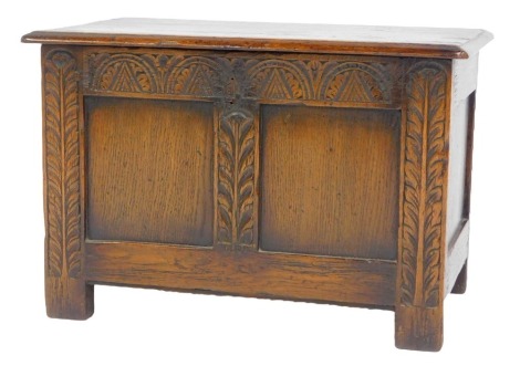 An oak small coffer, the rectangular top with a moulded edge enclosing a vacant interior, the panelled front decorated with carved leaf decoration, on stiles, 41cm high, 62cm wide, 36.5cm deep.
