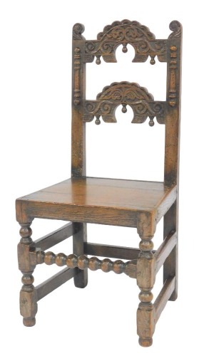 A late 17thC oak back stool, probably Yorkshire, with a carved back, solid seat, raised on turned legs united by plain and bobbin turned stretchers, 45cm wide.