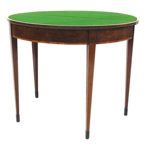 A George III mahogany fold over card table, with satinwood and rosewood cross banding, opening to reveal a baize interior, raised on tapering square legs, 74.5cm high, 92cm wide, 46cm deep.