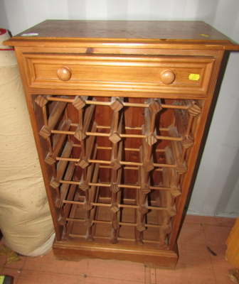 A pine wine rack, the top with a moulded edge above a drawer, the base with an arrangement of recesses for bottles, on bracket feet, 95cm high, 53cm wide, 30cm deep.