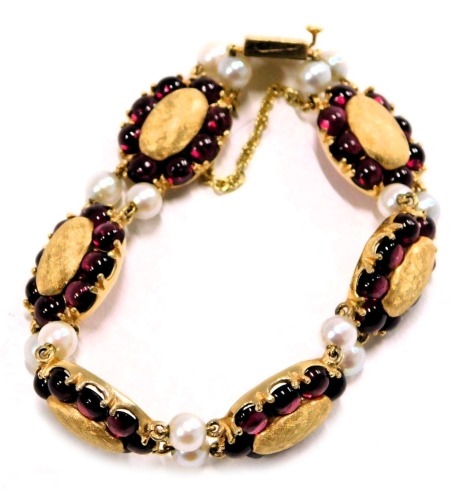 A Lucien Piccard Edwardian style bracelet, formed as oval sections set with cabochon rubies and two cultured pearl breaks, in yellow metal backing stamped 14k, with safety chain, 18cm long, 30.8g all in.