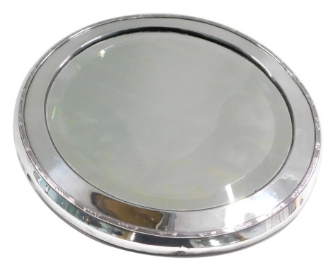 An Edward VII Mappin and Webb silver framed circular wall mirror, with a reeded outer border and bevelled plate, 28cm diameter, London 1909, on velvet lined back.