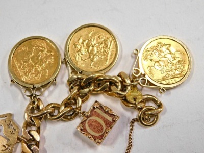 A 9ct gold charm bracelet, on curb link bracelet with safety chain and heart shaped padlocks, arrangement of charms to include five full gold sovereigns dated 1889, 1872, 1914, 1900 and 1899, note charms, etc., 14cm long, 93.3g all in. - 2