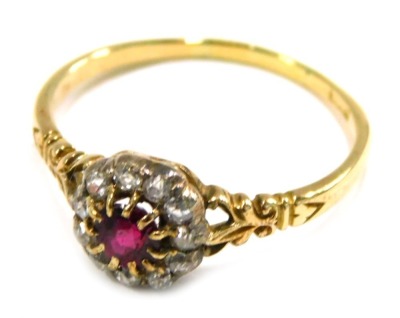 An Edwardian dress ring, formed as a cluster set with central garnet in claw setting surrounded by old cut tiny diamonds, with scroll design shoulders, on a yellow metal band, unmarked, ring size U, 3g all in.