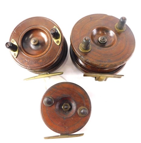 Three mahogany and brass fishing reels, various sizes.