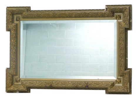 A gilt gesso wall mirror, the frame moulded with scrolls, etc., with a bevelled plate, 75cm high, 107cm wide.