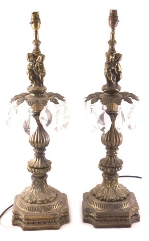 A pair of Continental gilt metal table lamps, each with cut glass drops and modelled with putti, leaves, etc., 73cm high overall.