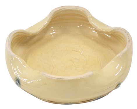 A Fenella Mallalieu studio pottery ashtray, with four point flared rim, applied green circular painted detail, on a striped foot, bearing signature, 17cm diameter.