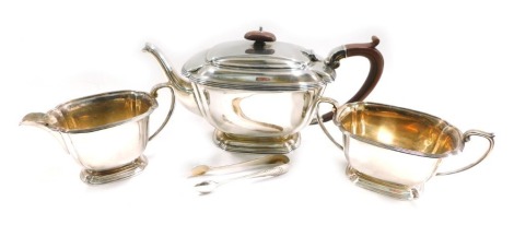 A George VI silver three piece tea set, in Art Deco style, with reeded borders and composition knop and handle, Birmingham 1940, 36.85oz gross, and a pair of silver plated sugar tongs.