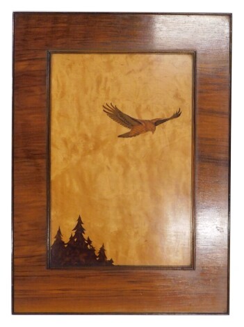 A mid 20thC marquetry picture of a buzzard flying above pines, titled Buzzard, in a walnut frame, 64cm x 46cm overall.