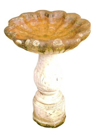 A reconstituted stone scallop shaped bird table, on a reeded acanthus leaf column, on hexagonal base, 73cm high, 45cm wide.