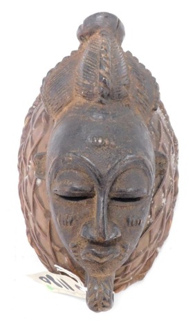 A Baule/Baoule Old Mblo portait mask with elaborate coiffure on basket, Cote D'Ivoire, approximately 65 years old, 27cm high.