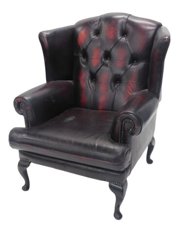 A leatherette finish studded wingback armchair, on cabriole legs.