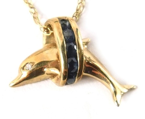 A 9ct gold pendant and chain, the pendant formed as a leaping dolphin, set with blue central stones and a white stone eye, 1.5cm wide, on fine link neck chain, 44cm long, 2.3g all in.