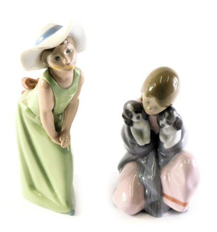 A Lladro porcelain figure group modelled as a young girl seated holding puppies, 6226, printed marks, 16.5cm high, together with a Lladro porcelain figure modelled as a young girl wearing hat and green dress, A14F, 23cm high. (AF)