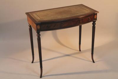 A Georgian style bow fronted writing desk with cylindrical reeded legs and leather gilt tooled top