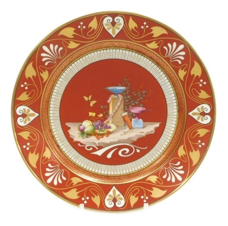 A mid 19thC Sevres Etruscan red ground hard paste porcelain dessert plate, decorated with a still life of fruit in a bowl, butterflies, cups on plinths, and a quiver of arrows, within a stylised gilt anthemion leaf and scroll border, Napoleon crowned 'N' 