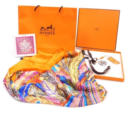 A Hermes orange silk scarf, decorated with a bejewelled and feather strewn head dress, boxed, 128cm x 126cm.