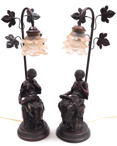 A pair of 19thC style simulated bronze table lamps, each modelled as a seated classical lady reading a book, with a pink tinted frosted glass floral shade, 53cm high. Buyer Note: WARNING! This lot contains untested or unsafe electrical items. It is suppli