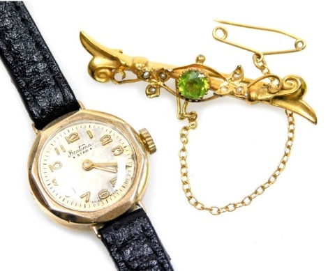 An Edwardian 9ct gold peridot and seed pearl set brooch, in a leaf and berry design, with safety chain as fitted, 2.9 grams, together with a Bentina lady's 9ct gold circular cased wristwatch, silvered dial bearing Arabic numerals, on a leather strap. (2)