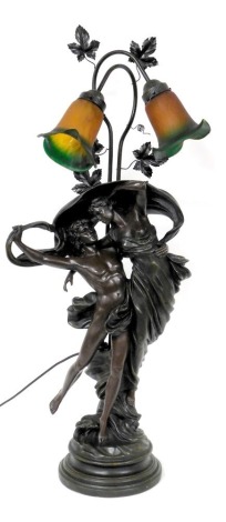 A bronzed plaster figural table lamp, modelled as Zephyr and Psyche, with two frosted orange to green frilled glass shades, 99cm high.