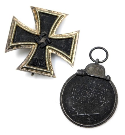 A Third Reich WWII Iron Cross 1939, first class breast badge, the pin marked with the number 65, together with an Eastern Medal. (2)