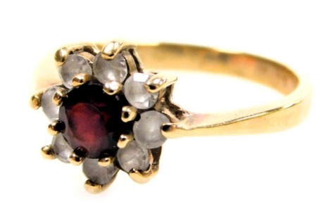 A 9ct gold flowerhead cluster ring, with a central brilliant cut ruby, surrounded by eight tiny white stones, 2.14g all in.