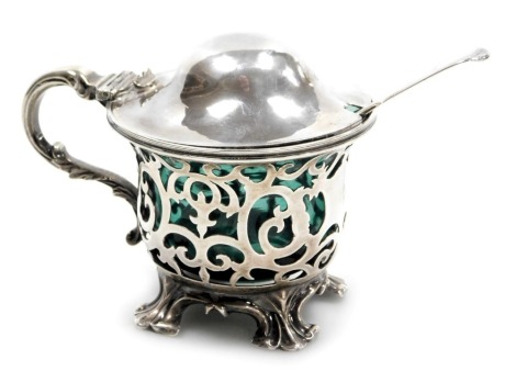 A Victorian silver mustard pot, with turquoise blue liner and pierced foliate decoration, raised on four leaf scroll feet, Joseph Angell I and Joseph Angell II, London 1846, together with a silver mustard spoon, monogram engraved, Chawner and Company, Lon