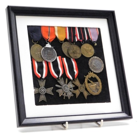 A group of German Third Reich medals, including two War Merit Crosses, Eastern Front metal, Naval Artillery badge, etc., with later ribbons, framed. (10)