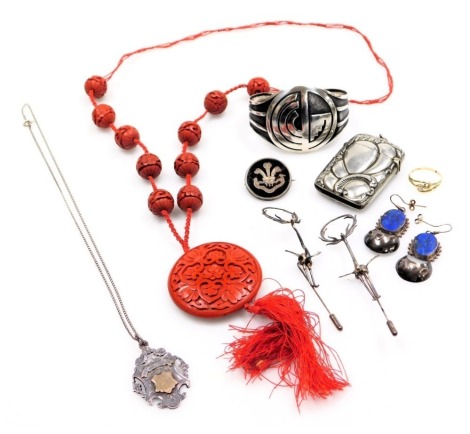 A Chinese cinnabar lacquer necklace on a silk cord, silver earrings, Welsh Regiment badge, silver medallion on chain, etc. (qty)