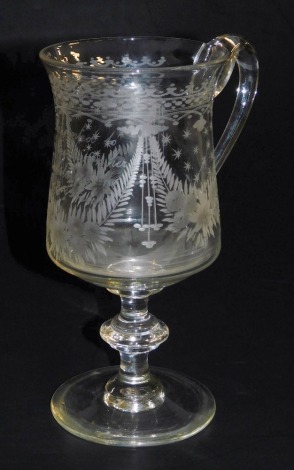 A late 19thC tankard, engraved with swags of flowers, and etched "Present to Lily Crocher on her birthday, Aug 2nd 188? by EG Sturch", raised on a central knopped stem and conical foot, 22cm high.