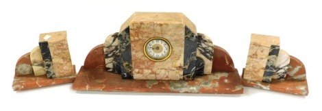 An Art Deco marble clock garniture, circular dial bearing Arabic numerals, German clockwork movement, the case of angular cloud form, in vary coloured marbles, raised on a rectangular base, clock 53cm wide, garniture sculptures 20cm wide a piece.