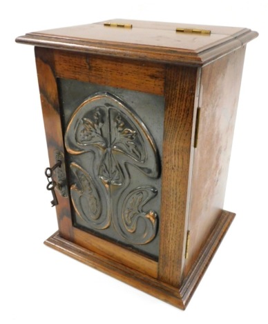 A Victorian Art Nouveau oak and copper panelled smoker's cabinet, with a hinged top and door embossed with stylized flowers, opening to reveal a pipe rack recess and single frieze drawer, raised on a plinth base, 28cm high, 21.5cm wide.