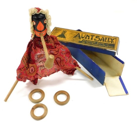 A late 19thC game of Aunt Sally, with a painted wooden and fabric bound figure, hoops, poles and pipe, boxed.