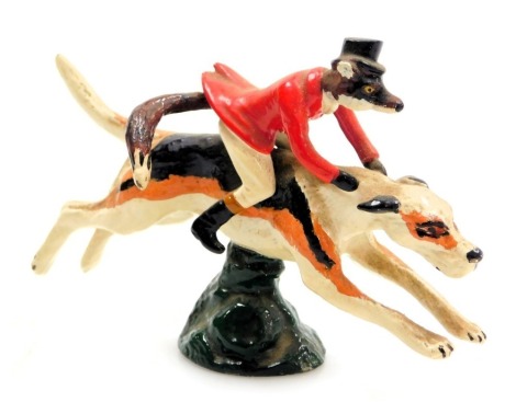 An LL Mascots cold painted brass car mascot, modelled as a fox in hunting attire atop a hound, 13cm wide.