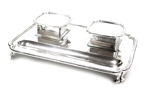 A George V silver desk stand, with a pair of hinged lidded glass inkwells, and pen recess, raised on corner paw feet, London 1919, 23.96oz.