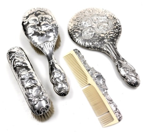 A Victorian and later composite three piece dressing table set, embossed with cherub's head, comprising hairbrush, London 1900, hand mirror, Chester 1908 and clothes brush London 1901, together with a silver mounted comb, embossed with flowers and scrolli