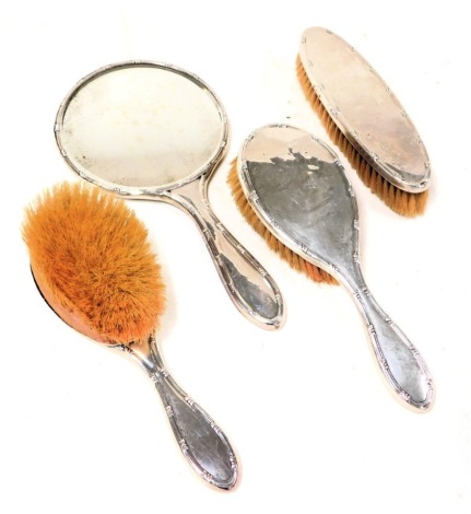 A George V silver backed four piece dressing table set, comprising a pair of hair brushes, clothes brush and hand mirror, Birmingham 1918.