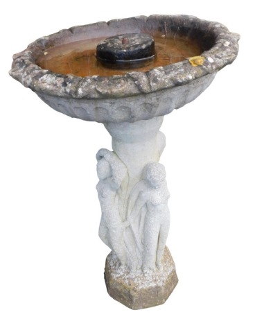 A concrete bird bath, the fluted bowl raised on a column flanked by the three graces, raised on an octagonal base, 79cm high.