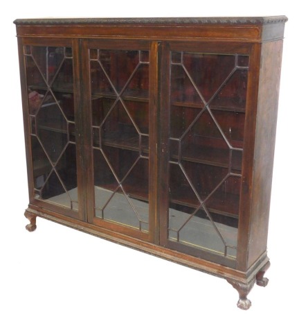 A late Victorian mahogany bookcase, with three astragal glazed doors enclosing three shelves, raised on foliate carved cabriole legs and ball and claw feet, 163cm high,180cm wide, 36cm deep.