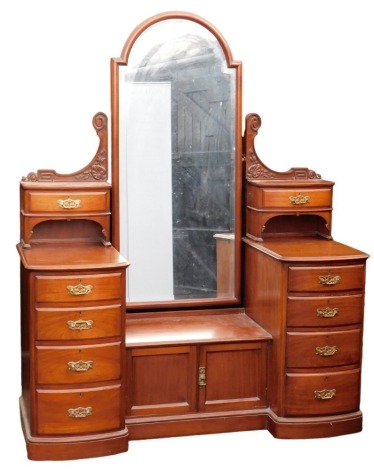 A Victorian mahogany dressing chest, the central domed mirror inset bevelled glass, flanked by a foliate carved super structure with two bow fronted drawers, above a pair of cupboard doors, flanked by two sets of five graduated drawers, raised on a plinth